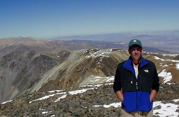 Demia Saffer stands in front of a dramatic mountain landscape.