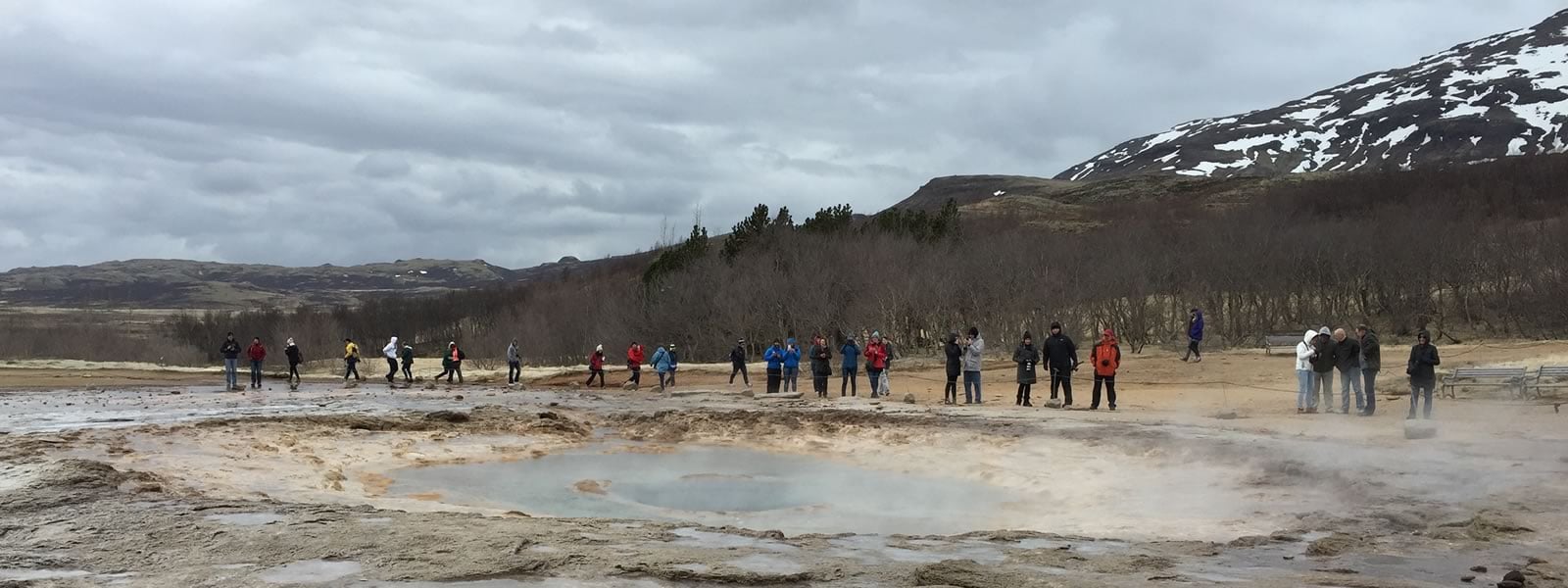 G3 students gather in front of a steamy pond on a field excursion to witness a geyser.